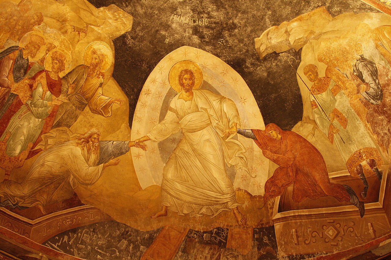 Cristo vestido de blanco toma de las muñecas a Adán y Eva y los levanta de sus sepulcros, sobre las puertas rotas del abismo.