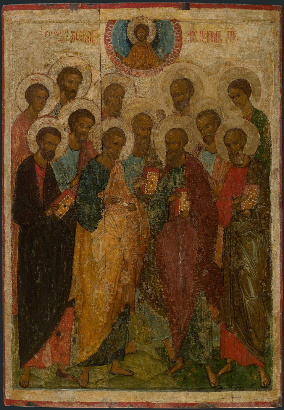 Doce figuras apostólicas con nimbos, libros y rollos se agrupan bajo un medallón de Cristo en un icono ruso antiguo.